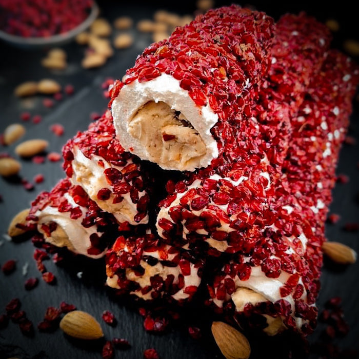 Piena-vaniļas lukums ar maigu mandeļu krēmu, pārkaisīts ar granātābola sēklām